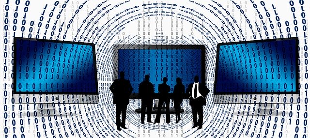 An image of the silhouettes of business people with three computer screens and binary code, representing the need for data management tools in business.