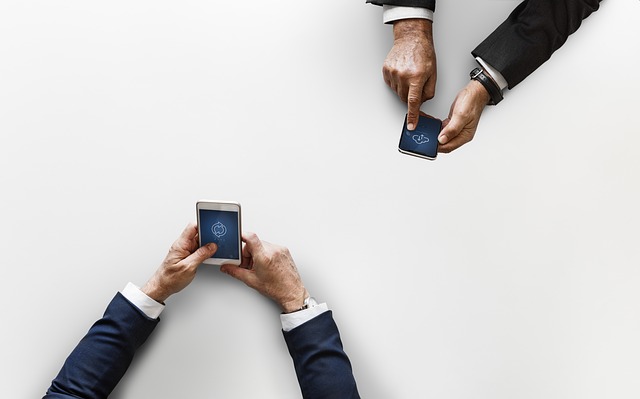 An image of two men holding mobile phones that are syncing or downloading data, representing the need for businesses to protect company data across devices.